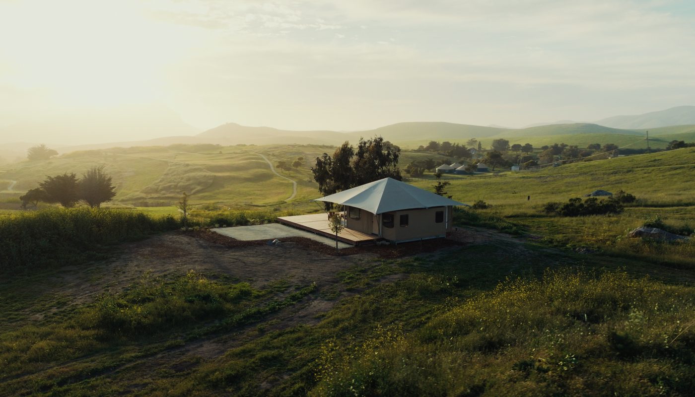 A Nightsky Camps tented suite on a hillside at golden hour, seen from above