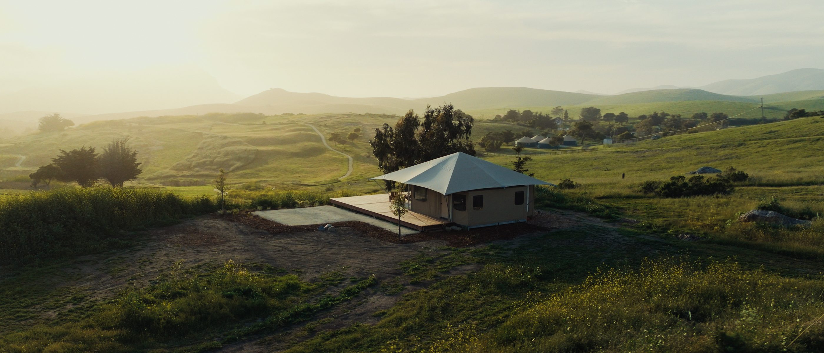 A Nightsky Camps tented suite on a hillside at golden hour, seen from above