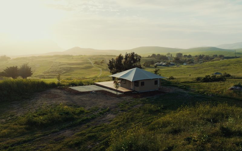 A Nightsky Camps tented suite on a hillside at golden hour, seen from above